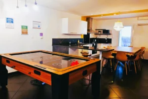 Loft Nature Bien Etre, field hockey on table and fully equipped and functional kitchen in the background vacation rental Tarn